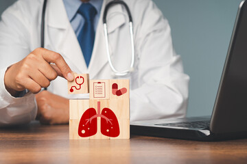 Lung and health icons on wooden cubes. A doctor is holding a wooden cube while sitting in the...
