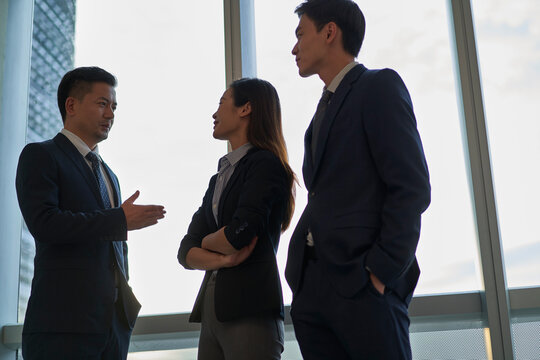 three asian businesspeople discussing business in office
