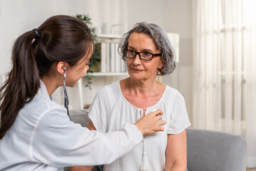 Fototapeta premium Asian caregiver nurse examine Caucasian senior woman patient at home. 
