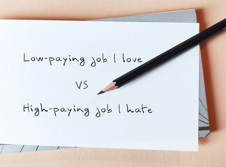 Pencil on notebook with handwriting on paper LOW-PAYING JOB I LOVE VS HIGH-PAYING JOB I HATE,...