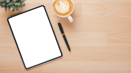 Office wooden desk workplace with blank screen tablet, pen and cup of coffee, Top view flat lay with copy space.