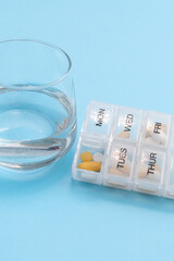 Weekly pill organizer with sunday open compartment and glass of water