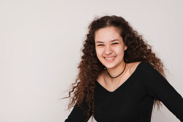 fashion female portrait. Smiling curly brunette girl posing beautifully at the camera on a white background. High quality photo