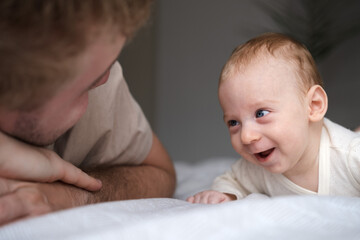 Cute two or three months baby boy looking at his parent or adult lying on belly on bed.Copy space.