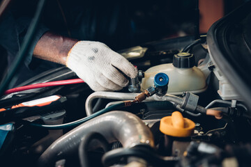 Mechanics inspect and check the refrigerant and fill the car air conditioner in the garage.