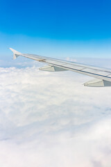 View from the airplane window at a beautiful cloudy sky and the airplane wing