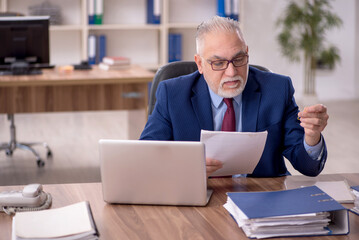 Old male employee working in the office