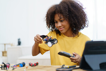 Happy cheerful American - African black ethnicity female university student learning about robotic and programing by herself, woman assemble a robot.