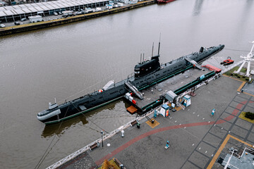 black submarine surfaced on the water in the city harbor.