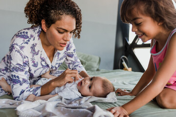 Obraz premium latin mother having fun with little baby on bed at home in Mexico Latin America, hispanic family