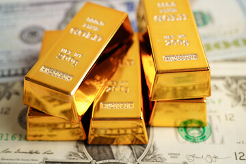 Gold bars on US dollar banknote money, finance trading investment business currency concept.