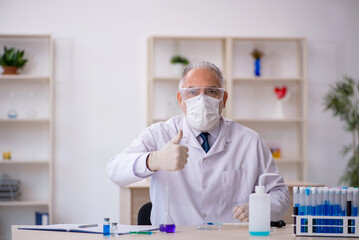 Old male chemist working at the lab