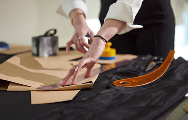 직선자를 사용해서 연필로 패턴을 그리는 여성 재단사의 손