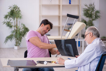 Obraz premium Young leg injured patient visiting old male doctor radiologist