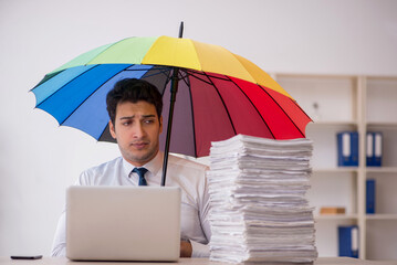 Young male employee holding an umbrella in the office