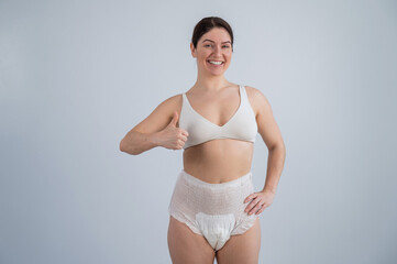 Woman in adult diapers smiling and showing thumbs up. Urinary incontinence problem.  - obrazy, fototapety, plakaty