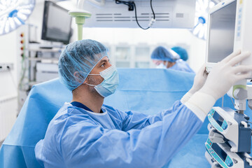 Anesthesiologist keeping track of vital functions of the body during cardiac surgery. Surgeon...