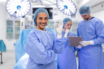 Close-up of a surgeon woman looking at camera with colleagues performing in background in operation...