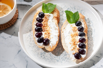 An appetizer of a sandwich with cheese, grapes, nuts and mint greens. Tea with lemon.