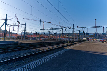 Fototapeta na wymiar Platform at railway station with train at Swiss City of Luzern with Swiss Alps in the background on a sunny spring day. Photo taken March 22nd, 2023, Lucerne, Switzerland.