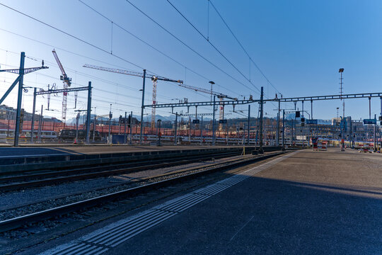 Platform at railway station with train at Swiss City of Luzern with Swiss Alps in the background on a sunny spring day. Photo taken March 22nd, 2023, Lucerne, Switzerland.