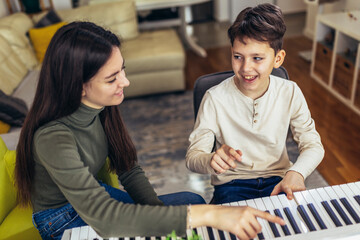 Brother and sister play electric piano at home and have fun.