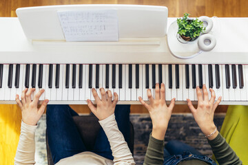 Children practicing on the modern electric piano at home. Music lesson. Close-up.