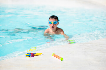 A Caucasian elementary school boy plays in the pool.