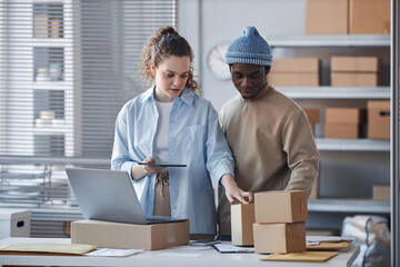 Young female manager explaining colleague where to look for address of receiver on box while...