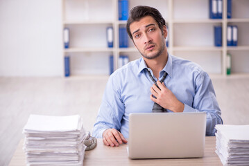 Young male employee and too much work at workplace