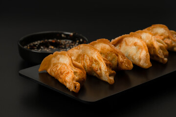 Gyoza, dumplings with soy sauce on dark background