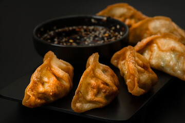 Gyoza, dumplings with soy sauce on dark background