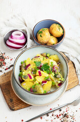 Delicious new potato salad with red onion, capers, greens in a bowl.