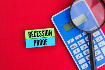 calculator and magnifying glass with words recession proof. recession proof concept