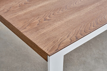 Minimalism style dining table with thin wooden table top of toned oak veneer on white metal legs closeup