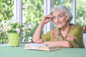 Beautiful elderly woman reads a book at the country house