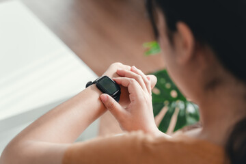 young woman looking and using a smartwatch, Female sitting on the sofa checking her smartwatch.