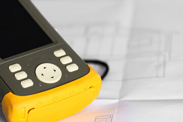 Modern GPS system field controller on Architecture Building Plan. Surveyor engineering and...