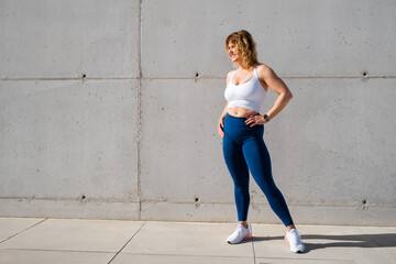 Woman wearing sportswear of white sports bra and blue leggings - obrazy, fototapety, plakaty