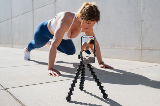 Woman film herself on mobile phone and live streaming her fitness workout on social media