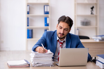 Obraz premium Young male employee and too much work in the office