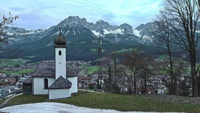 View from a chapel to a little town in a valley to snow covered mountains in the background - winter holidays location