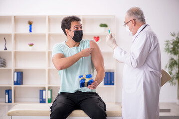 Fototapeta premium Old male doctor giving giftbox to young male patient