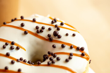 Appetizing donut covered with caramel and crispy balls, macro shot.
