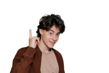 Handsome teenager boy in green brown jacket points by  index finger up at workspace area isolated on plain transparent background portrait. Mockup, sale, discount. Idea! Happy guy looks at camera