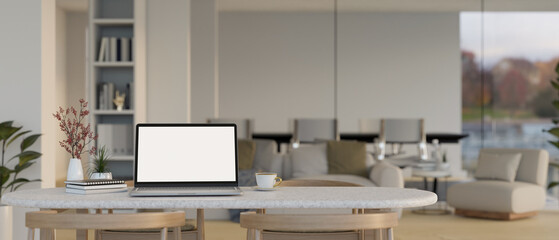 Close-up image of a laptop mockup and accessories on a table in modern contemporary living room.
