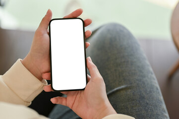 A female relaxing on a sofa and using her smartphone, close-up image