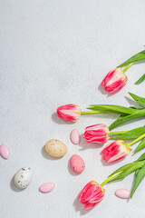 Pink tulips with Easter eggs on light stone concrete background. Festive concept, greeting card