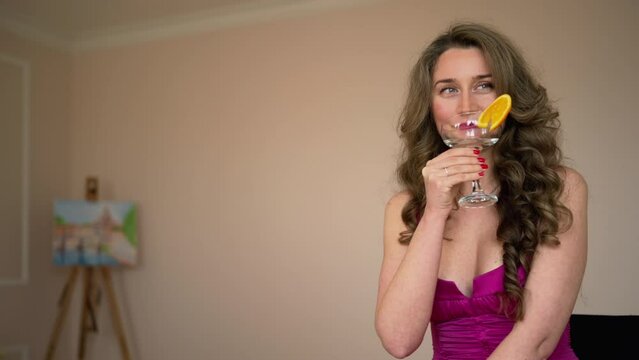 Woman In Red Dress Drinking A Cocktail With Orange Slice At Home