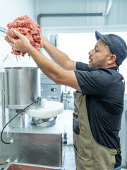 butcher man putting the minced meat into the hamburger making machine